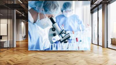 biochemical research scientist team working with microscope for coronavirus vaccine development in pharmaceutical research labolatory Wall mural