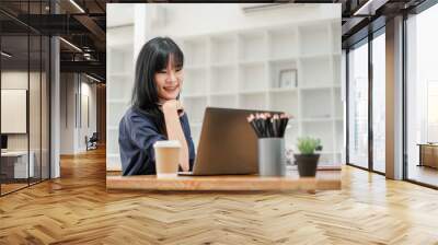 Cheerful businesswoman with braces smiling while working on her laptop in a bright, contemporary office space. Wall mural