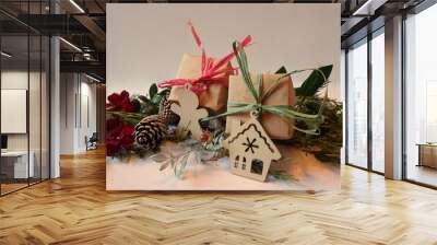 Two Kraft Wrapped Gift Boxes with Raffia, Wooden Christmas Cutouts, Greenery and Pinecones on White Background Wall mural