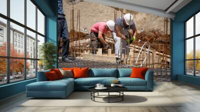 Male workers working on the retaining wall, tying rebar and reinforcement bar at the construction site. Wall mural