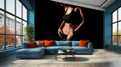 Close up sexy girl shows her perfect body and sports stomach. Healthy fitness and eating lifestyle concept. Fitness sporty woman showing her well trained body, isolated over black background. Wall mural