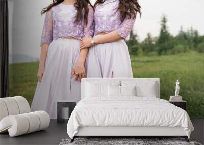 Two beautiful bridesmaids girls brunette ladies wearing full length lavender tulle one shoulder bridesmaid dress. European mountains location for wedding day. Wedding concept. Wall mural