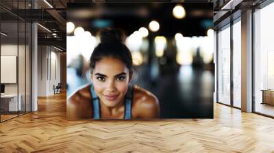 determined fit brunette woman runner training in a fitness center, focusing on strength and endurance posing with smiled face expression, copy space Wall mural