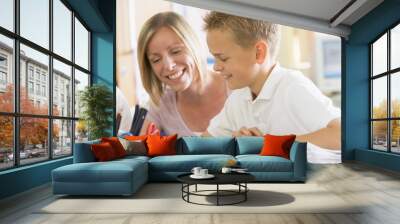 A schoolboy sitting with his teacher in class Wall mural