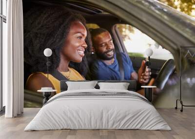 A young black man checks smartphone during a road trip Wall mural