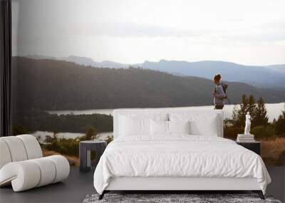 A young mixed race man standing alone on the rock, watching lake view, landscape Wall mural