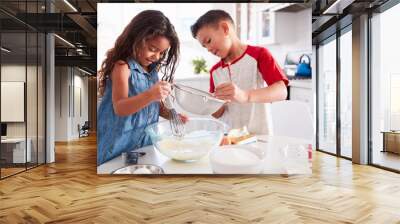 Brother and sister preparing cake mixture together at the kitchen table, waist up Wall mural