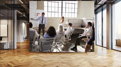 Business group watching a male colleague give a presentation Wall mural