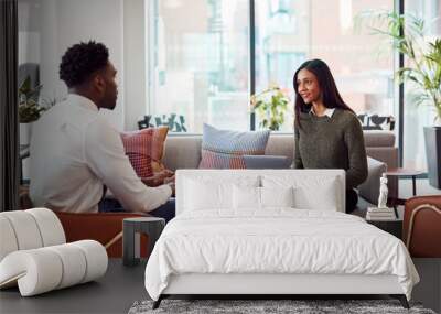 Businesswoman Interviewing Male Job Candidate In Seating Area Of Modern Office Wall mural