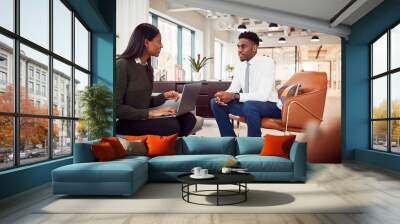 Businesswoman Interviewing Male Job Candidate In Seating Area Of Modern Office Wall mural