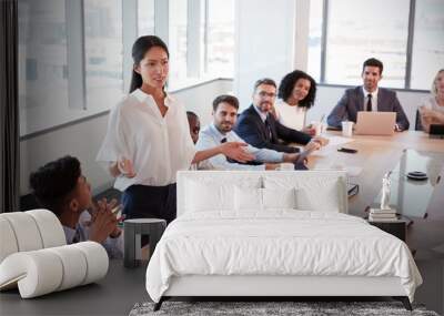 businesswoman stands to address meeting around board table Wall mural