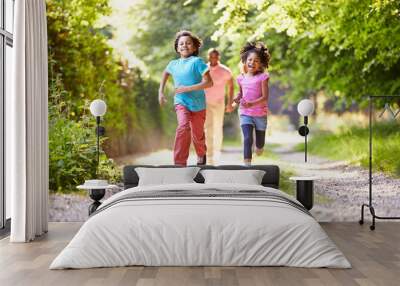 children running in countryside with father Wall mural