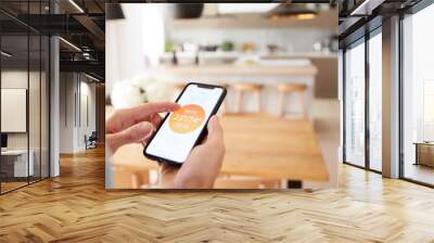 Close Up Of Man Using App On Smart Phone To Control Central Heating Temperature In House Wall mural