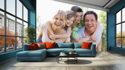 Couple giving two young children piggyback rides smiling Wall mural