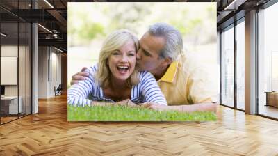 Couple relaxing outdoors in park kissing and smiling Wall mural