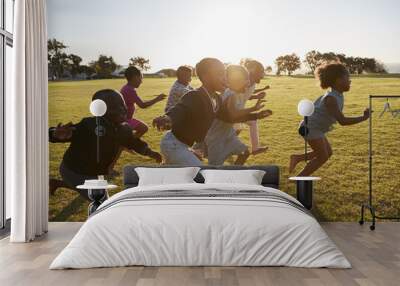 Elementary school kids running together in an open field Wall mural