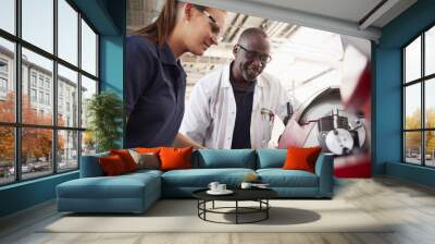 Engineer showing female apprentice how to operate machinery, close up Wall mural