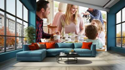 family enjoying meal in restaurant together Wall mural