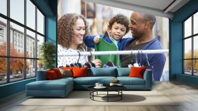 Family Looking At Clothes On Rail In Shopping Mall Wall mural