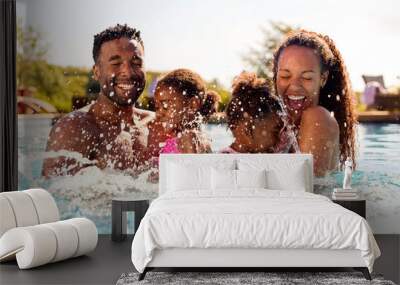 Family On Summer Holiday With Two Girls Being Held In Swimming Pool By Parents And Splashing Wall mural