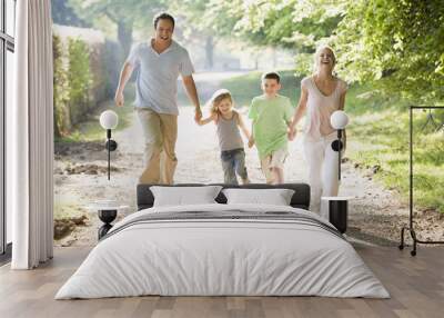 family running outdoors holding hands and smiling Wall mural