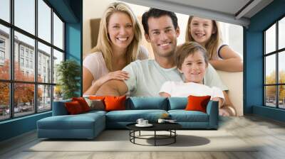 Family sitting in living room smiling Wall mural