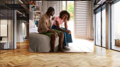 Father Talking With And Comforting Unhappy Teenage Daughter With Problem Sitting On Bed At Home Wall mural