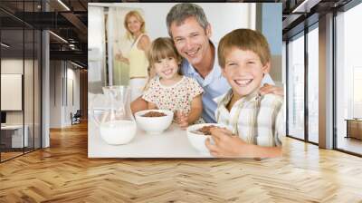 father with children as they eat breakfast and mother in the bac Wall mural