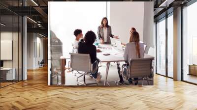 Female Boss Gives Presentation To Team Of Young Businesswomen Meeting Around Table In Modern Office Wall mural