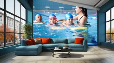 Female Coach In Water Giving Group Of Children Swimming Lesson In Indoor Pool Wall mural