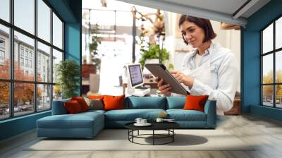 Female Owner With Digital Tablet Standing Behind Sales Desk Of Florists Store Wall mural