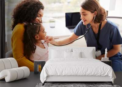 Female Pediatrician Wearing Scrubs Listening To Girls Chest With Stethoscope In Hospital Office Wall mural