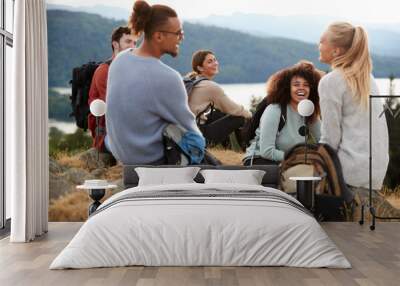 Five young adult friends sit talking at the summit after a mountain hike, close up Wall mural