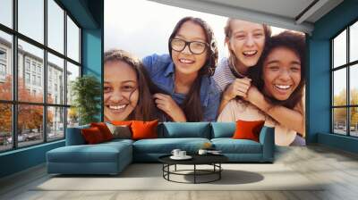 Four teenage girls having fun piggybacking outdoors Wall mural