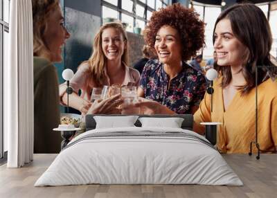 Four Young Female Friends Meeting For Drinks And Food Making A Toast In Restaurant Wall mural