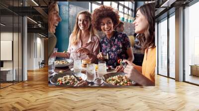 Four Young Female Friends Meeting For Drinks And Food Making A Toast In Restaurant Wall mural