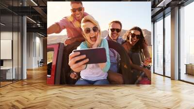 Friends On Road Trip In Convertible Car Taking Selfie Wall mural