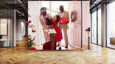 Grandchildren Greeting Grandparents As They Arrive With Presents To Celebrate Christmas Wall mural