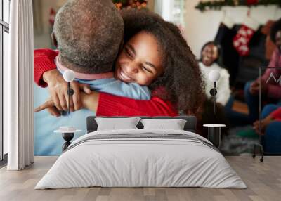 Granddaughter Giving Grandfather Hug As Multi Generation Family Celebrate Christmas At Home Wall mural