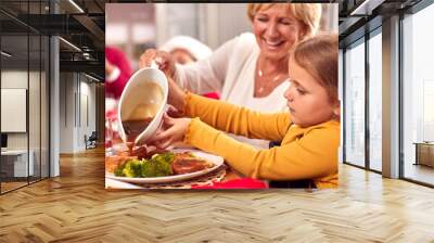 Grandmother Pouring Gravy Onto Granddaughters Food As Multi-Generation Family Eat Christmas Meal Wall mural