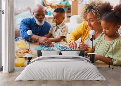 Grandparents With Grandchildren Indoors At Home Doing Jigsaw Puzzle With Parents In Background Wall mural