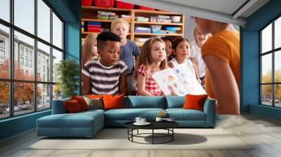 Group Of Elementary School Pupils Sitting On Floor Listening To Female Teacher Read Story Wall mural