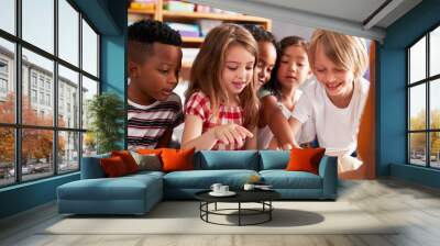 Group Of Elementary School Pupils Sitting On Floor Listening To Female Teacher Read Story Wall mural