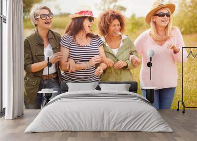 Group Of Mature Female Friends Walking Along Path Through Yurt Campsite Wall mural