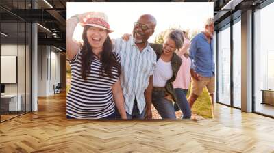 Group Of Mature Friends On Vacation Walking Along Path Through Campsite At Sunset Wall mural