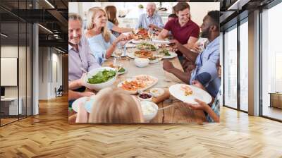 Group Of Multi-Generation Family And Friends Sitting Around Table And Enjoying Meal Wall mural