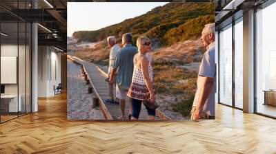 group of senior friends walking along boardwalk at beach on summer group vacation Wall mural