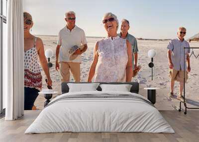 Group Of Senior Friends Walking Along Sandy Beach On Summer Group Vacation Wall mural