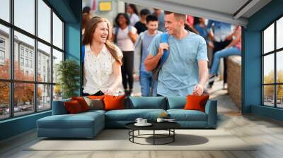 Group Of Smiling Male And Female College Students Walking And Chatting Outside School Building Wall mural