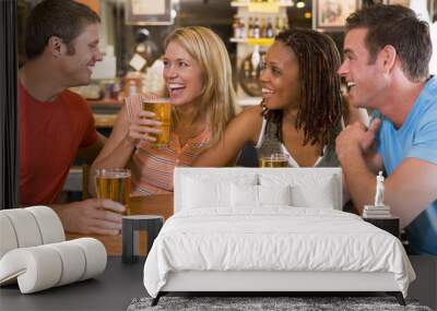 Group of young friends drinking and laughing in a bar Wall mural